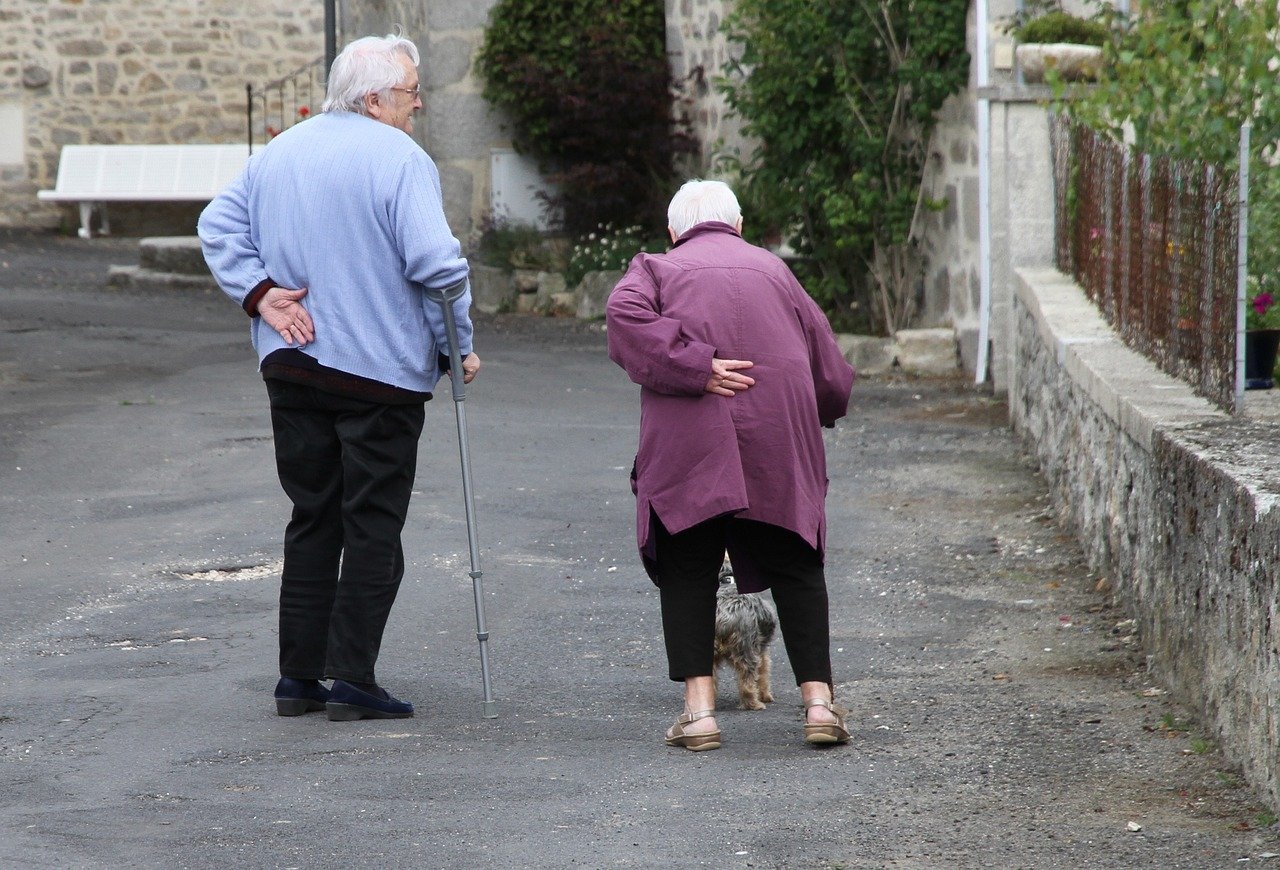 Elderly couple walking together, supporting each other on a quiet path. The image captures the essence of care and companionship, highlighting the challenges the care sector may face following the abolition of the UK Care Worker Visa Route.