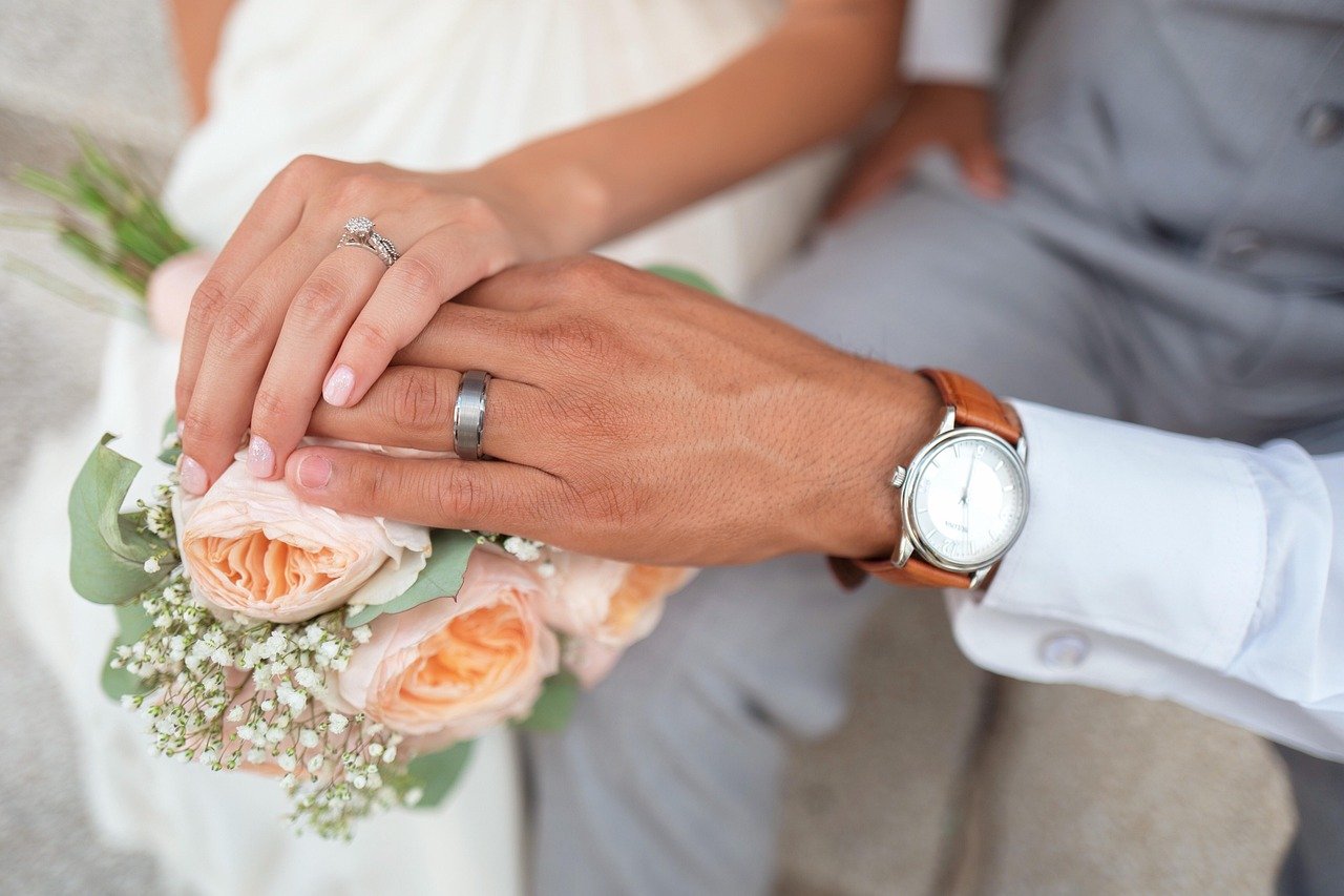 Couple showing wedding rings with bouquet – symbolic of Scotland marriage age debate